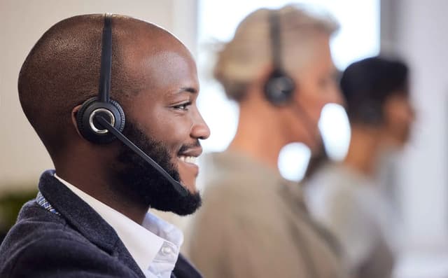 A HOMIDAZ counsellor wearing a headset, smiling while he talks a student through their UK application