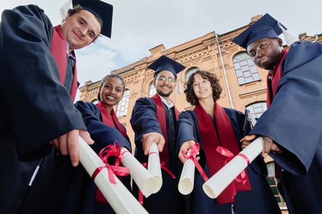 University graduates in caps and gowns celebrating with their diplomas